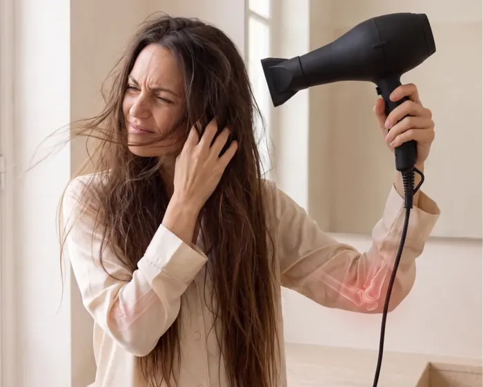Woman holding a conventional dryer overhead with her arm and shoulder aching
